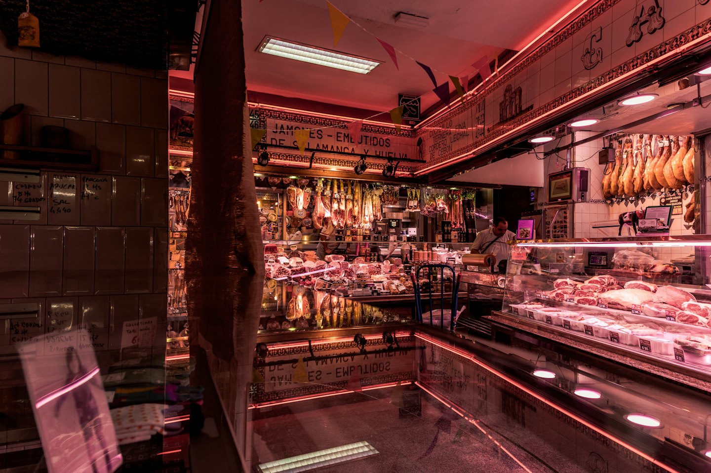 A butcher works behind a meat counter in a shop.